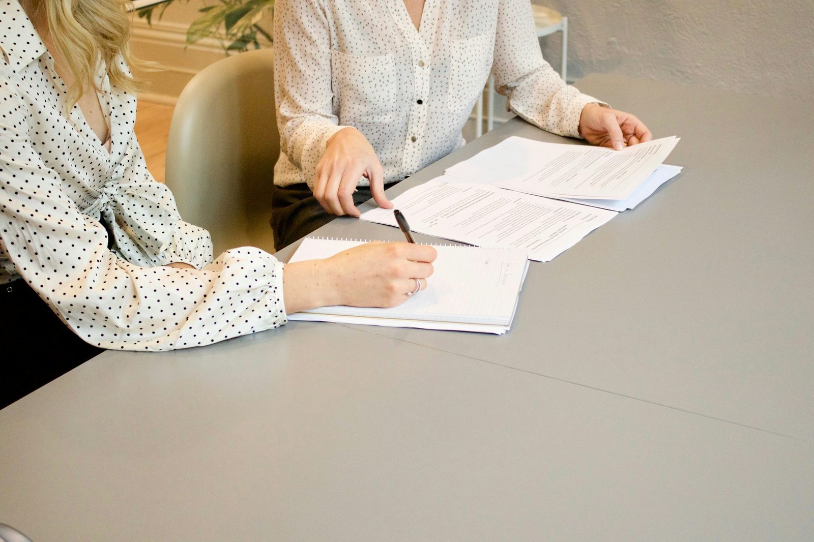 Two people at a table going through a stack of printed claims and taking notes